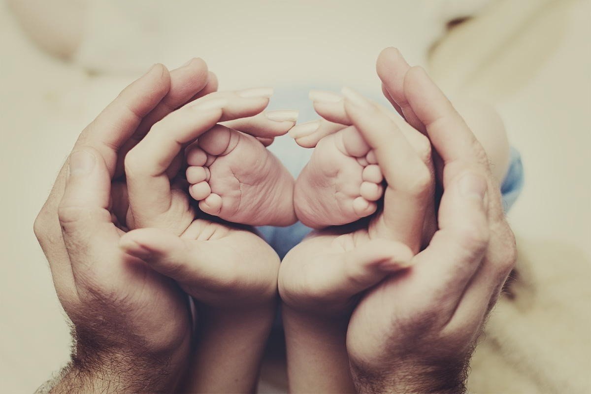 Ножки младенца в руках мужчины и женщины